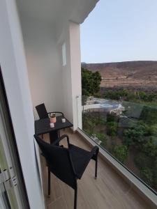 a balcony with a table and a chair and a window at Alojamientos Agaete Pueblo Nº3 in Agaete