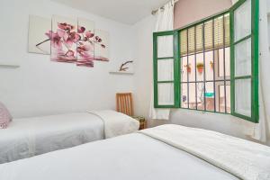Dos camas en una habitación con ventana. en Casa Victoria G, en Nerja