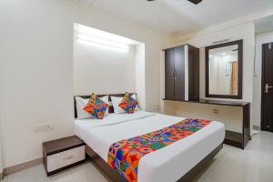 a bedroom with a large bed and a mirror at FabHotel Destination 42 - Nr Pheonix Mall in Kharadi