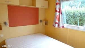a small bedroom with a bed and a window at Mobil-home Camping 3 étoiles in Genouillé