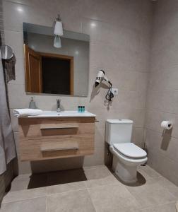 a bathroom with a toilet and a sink and a mirror at Vivienda de uso turistico AT in Tomelloso