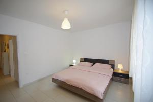 a bedroom with a bed with a pink blanket at Apartments Nikolina in Rakalj