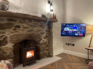 ein Wohnzimmer mit einem Steinkamin und einem TV in der Unterkunft Cabra Cottage in Kilcoo