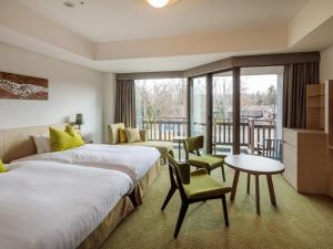 two beds in a hotel room with a balcony at Hakuba Tokyu Hotel in Hakuba