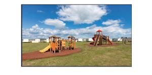 a park with two playground equipment in a field at Harts Holiday Park Kent London in Leysdown-on-Sea