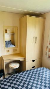 a bedroom with a bed and a cabinet and a mirror at Harts Holiday Park Kent London in Leysdown-on-Sea
