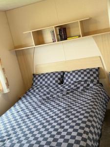 a bed in a small room with a checkered bedsheet at Harts Holiday Park Kent London in Leysdown-on-Sea +33 photos