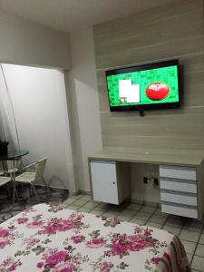 1 dormitorio con 1 cama y TV en la pared en Costeira Praia Flat 119, en Natal