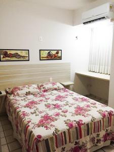 a bedroom with a bed with a floral bedspread at Costeira Praia Flat 119 in Natal