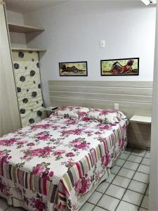 a bedroom with a bed with a floral bedspread at Costeira Praia Flat 119 in Natal