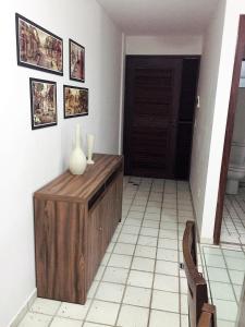 a room with a wooden cabinet and a vase on a wall at Costeira Praia Flat 119 in Natal
