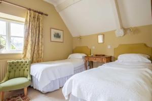 a bedroom with two beds and a chair and a window at Bookers Cottage in Bruern +17 photos