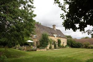 a large stone house with a grass yard at Bookers Cottage in Bruern