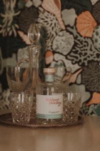 a bottle and glasses on a table with a wall at Quaint and intimate 1-bed seaside cottage in Bridport