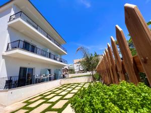 a white house with a wooden fence and bushes at The Gwen in Sarandë