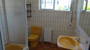 a bathroom with a yellow toilet and a sink at Casa de Lolo en Lariño cerca de la playa in San Mamede de Carnota +22 photos