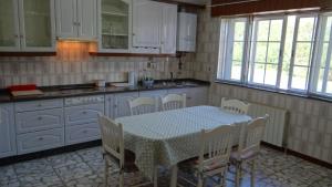 a kitchen with a table and white cabinets and a table and chairs at Casa de Lolo en Lariño cerca de la playa in San Mamede de Carnota