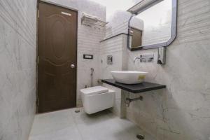 a white bathroom with a sink and a toilet at FabHotel Narula in Dehradun