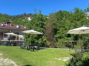 a yard with tables and umbrellas in front of a house at Casa Seggiovia in Frabosa Soprana