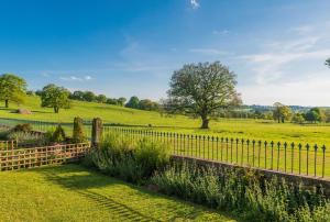 a fence in a field with a tree at Heathy Lea BarnChatsworth Estate in Baslow