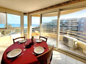 a dining room with a red table and a view of the ocean at Canet-en-Roussillon T3 - 4 pers, CLIM, WIFI, PARKING, Loggia, 3 étoiles - FR-1-794-139 in Canet-en-Roussillon