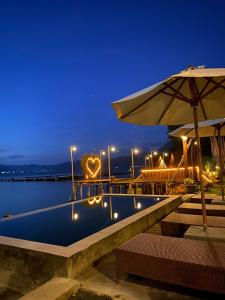 a swimming pool with an umbrella and a heart sign at EMaYan Glamping in Kubupenlokan