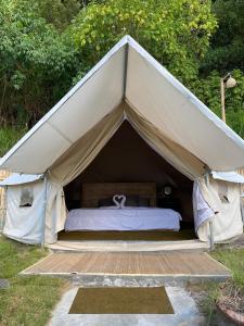 a tent with a bed in the grass at EMaYan Glamping in Kubupenlokan +14 photos