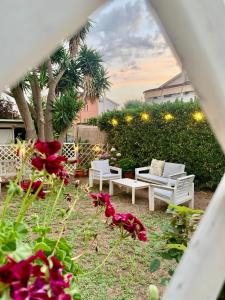 a garden with white chairs and red flowers at B&B Villa Pietrachiara in Bari
