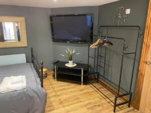 a bedroom with a bed and a flat screen tv at Bar Lodge in Ilkeston
