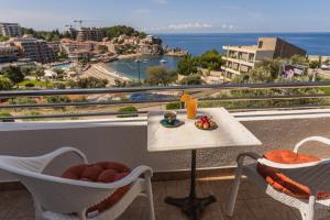 a table and chairs on a balcony with a view of the ocean at Apartments Raymond in Sveti Stefan