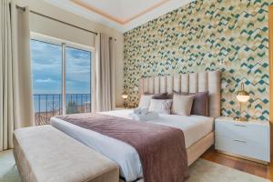 a bedroom with a large bed with a large window at Balancal Apartments and Villas Palheiro Village by Holiday Rental Madeira in Funchal