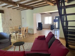 a living room with a red couch and a table at Maison de la petite sorcière in Razac-de-Saussignac +2 photos