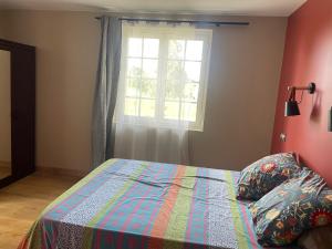 a bedroom with a bed with a colorful quilt and a window at Maison de la petite sorcière in Razac-de-Saussignac