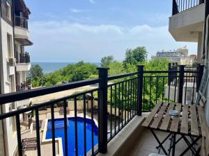 a balcony with a bench and a swimming pool at Бяла Виста Бийч Апартментс A - Byala Vista Beach Apartments A in Byala