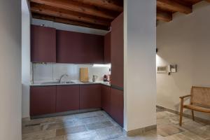 a kitchen with burgundy cabinets and a sink at Cosy renovated flat in the center in Padenghe sul Garda