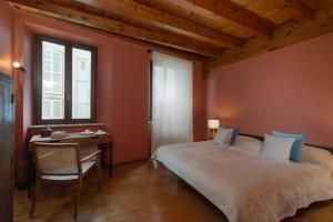 a bedroom with a bed and a desk and a window at Cosy renovated flat in the center in Padenghe sul Garda