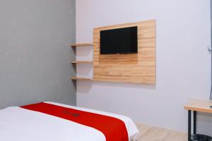a room with a bed and a tv on a wall at RedDoorz near Alun Alun Kembangjoyo Pati in Pati