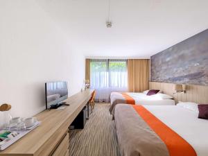 a hotel room with two beds and a flat screen tv at Mercure Gdańsk Posejdon in Gdańsk