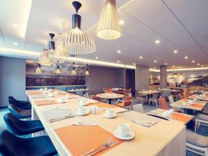 a dining room with tables and chairs and chandeliers at Mercure Gdańsk Posejdon in Gdańsk