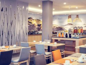 a restaurant with tables and chairs and a mural at Mercure Gdańsk Posejdon in Gdańsk