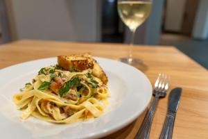 a plate of pasta on a table with a glass of wine at Hampton By Hilton San Jose Airport Costa Rica in Alajuela City