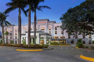 a white building with palm trees in front of it at Hampton By Hilton San Jose Airport Costa Rica in Alajuela City