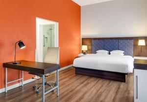 an orange room with a bed and a desk at Hampton By Hilton San Jose Airport Costa Rica in Alajuela City
