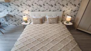 a bedroom with a large bed with two lamps on tables at Promenade Apartment in Liepāja