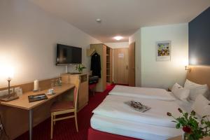 a hotel room with two beds and a desk at Hotel Mainpromenade ***S in Karlstadt