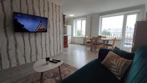a living room with a couch and a tv on a wall at Promenade Apartment in Liepāja