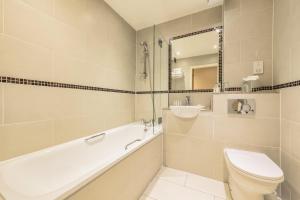 a bathroom with a tub and a toilet and a sink at Holyrood Aparthotel in Edinburgh