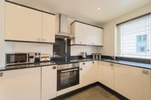 a kitchen with white cabinets and a microwave at Holyrood Aparthotel in Edinburgh