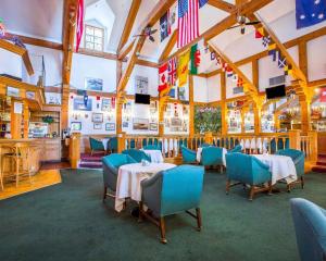 a dining room with tables and chairs and flags at Clarion Inn Near China Lake Naval Station in Ridgecrest
