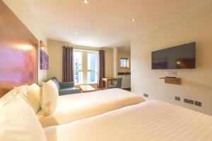 a hotel room with two beds and a flat screen tv at Holyrood Aparthotel in Edinburgh